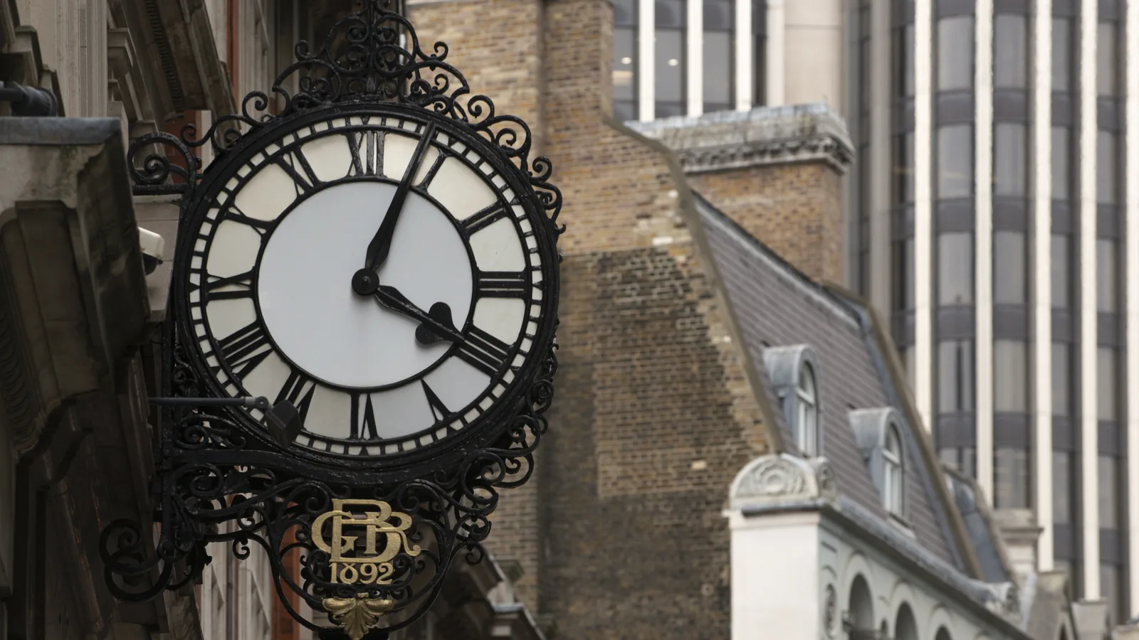An ornate street clock on a stone building in the City of London.