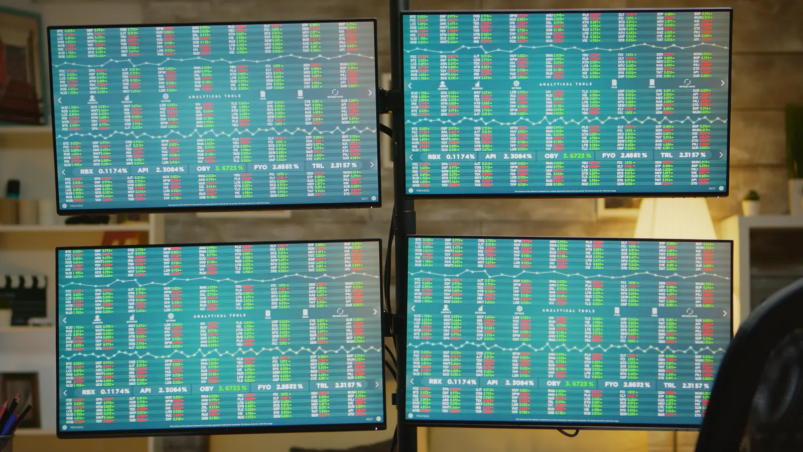 Several monitors showing stock market tables on a trading desk.