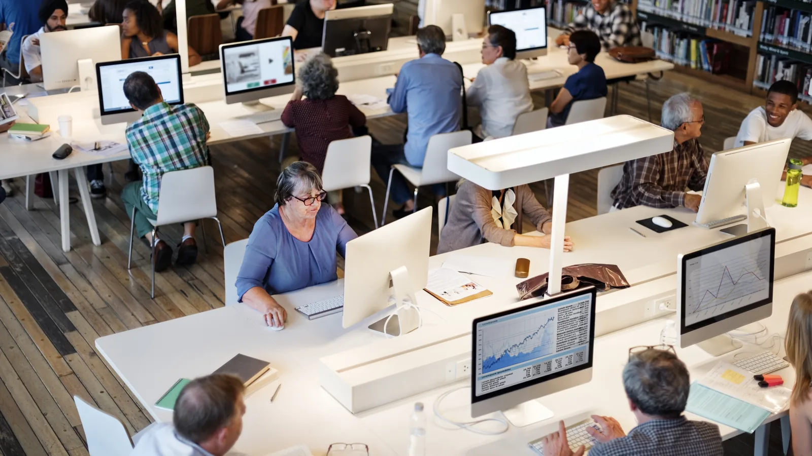 People working at computers in a bright open-plan office.