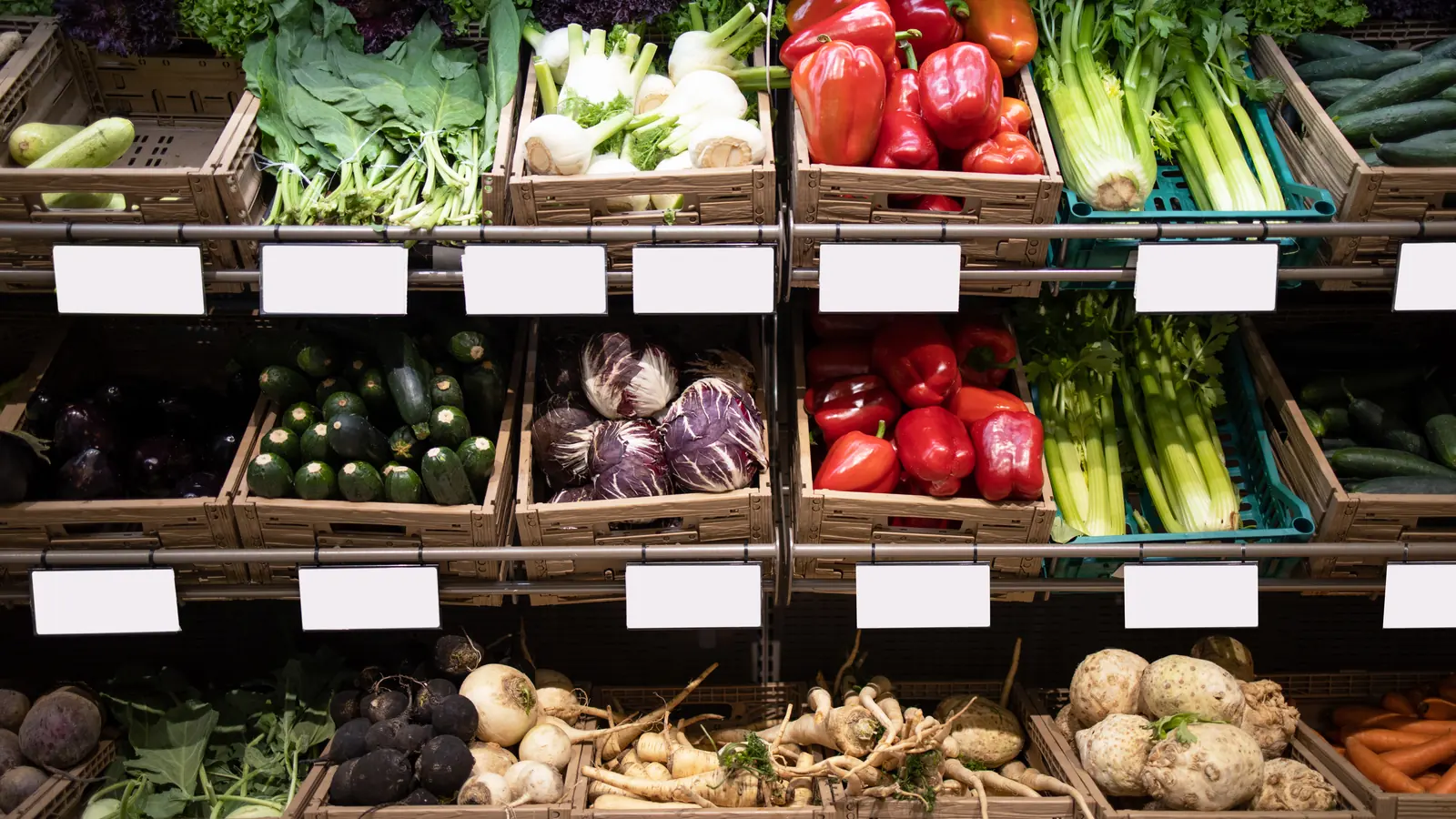 Grocery shelves stocked with fresh vegetables and price tags.
