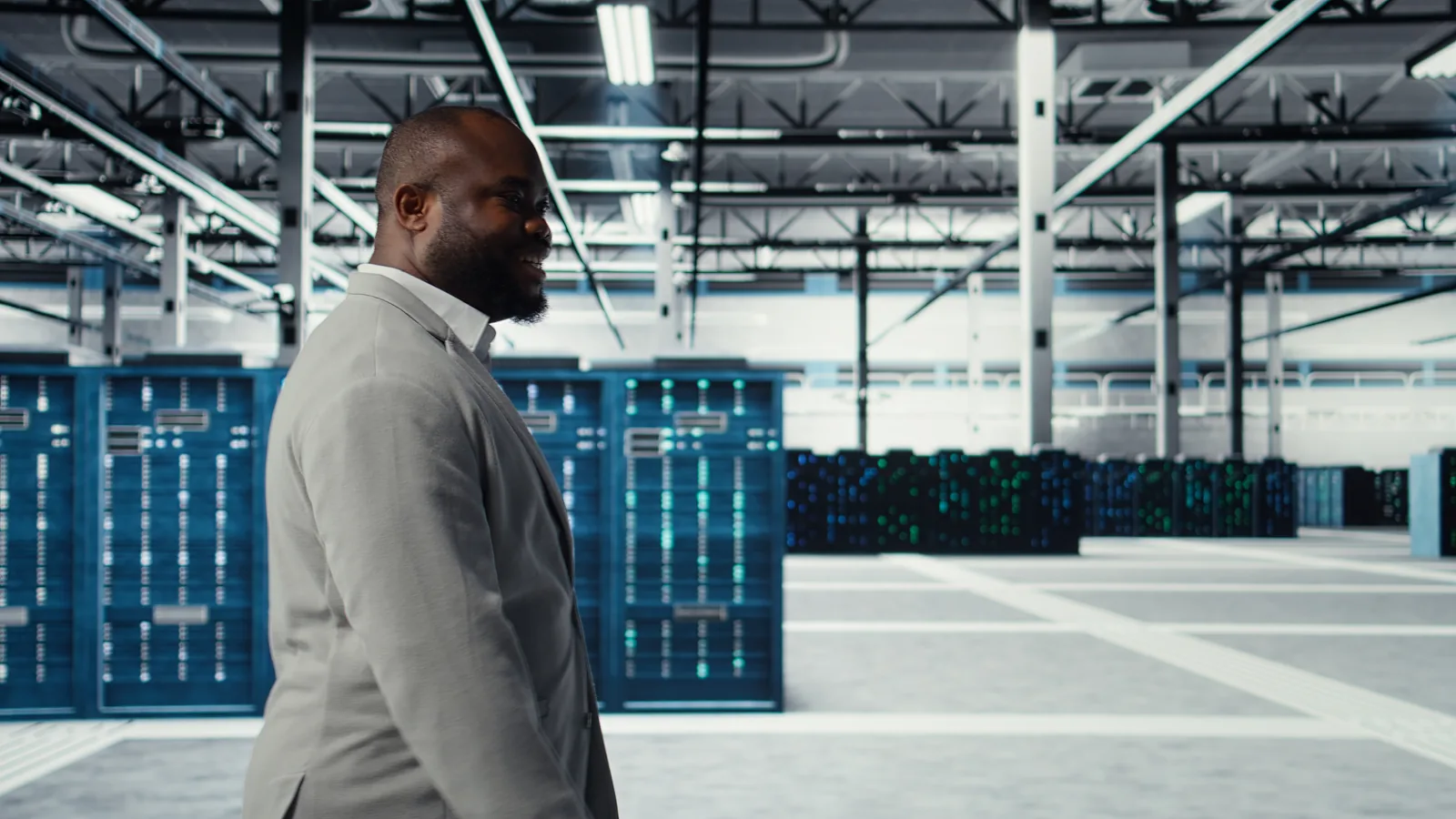 A data center technician walks an aisle between rows of server racks.